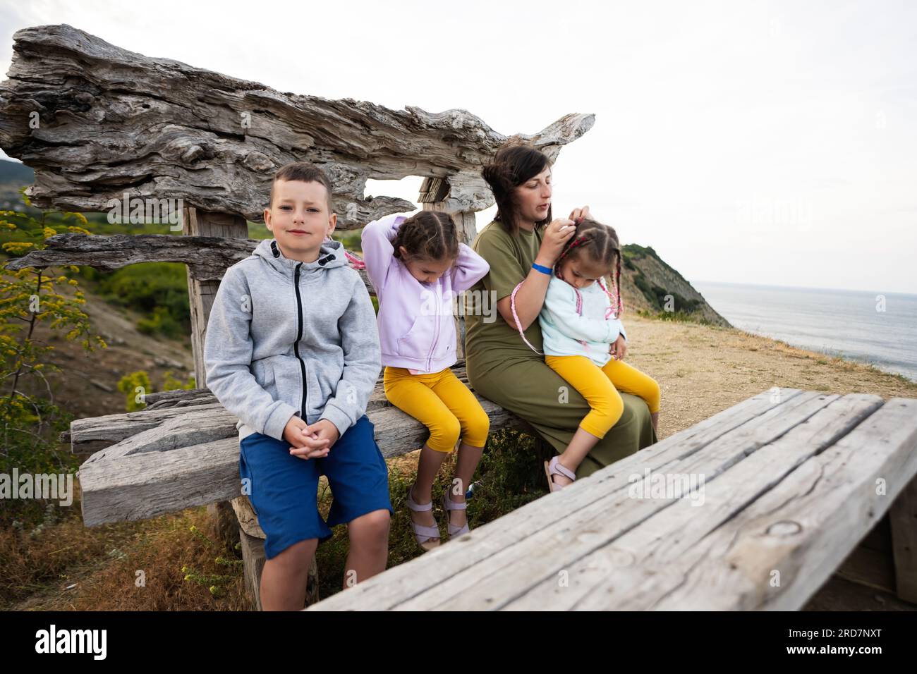 Famiglia felice seduto su una panchina di legno e guardando il mare. Capo Emine, costa del Mar Nero, Bulgaria. Foto Stock