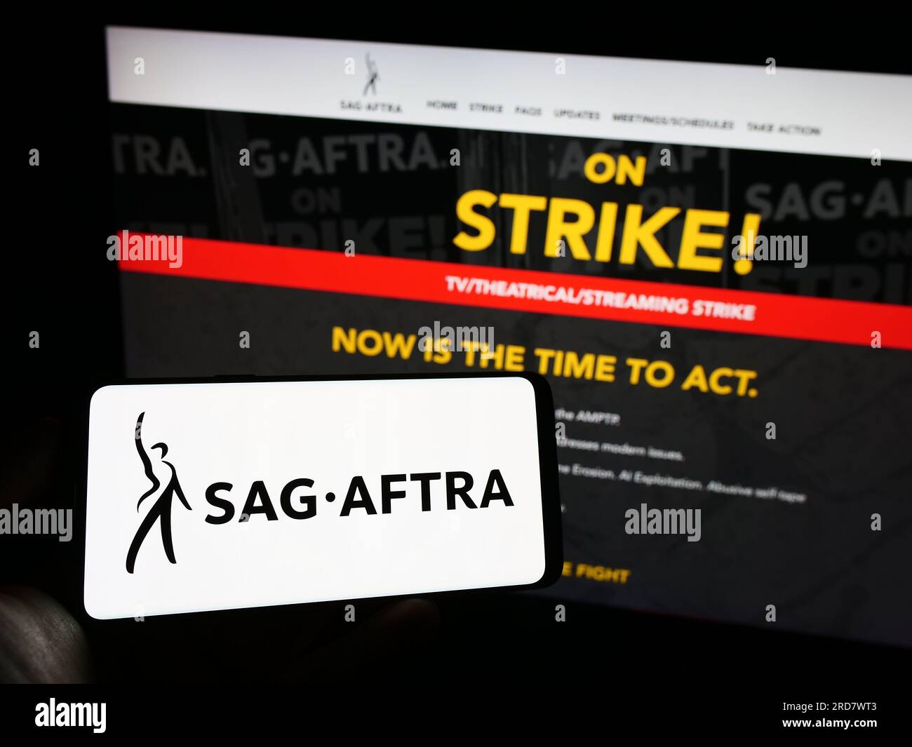 Persona in possesso di un cellulare con il logo del sindacato SAG-AFTRA degli Stati Uniti sullo schermo davanti alla pagina Web. Concentrarsi sul display del telefono. Foto Stock