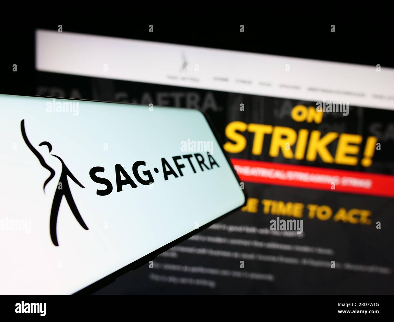 Smartphone con logo del sindacato SAG-AFTRA degli Stati Uniti sullo schermo davanti al sito Web. Mettere a fuoco il display centrale sinistro del telefono. Foto Stock