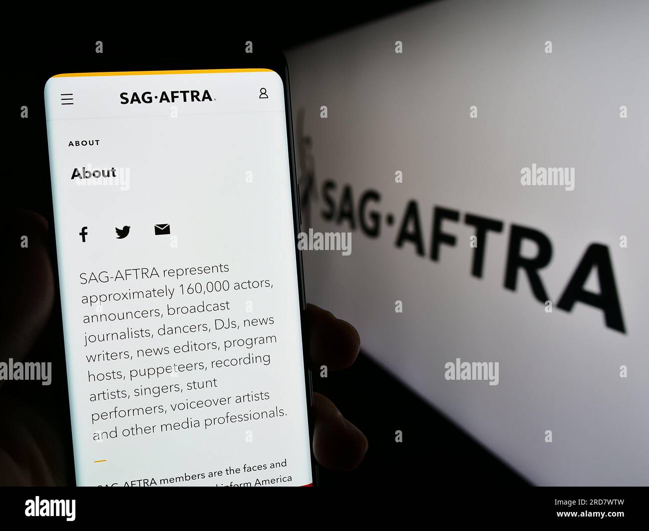 Persona in possesso di un cellulare con il sito Web del sindacato SAG-AFTRA degli Stati Uniti sullo schermo davanti al logo. Concentrarsi sul centro del display del telefono. Foto Stock