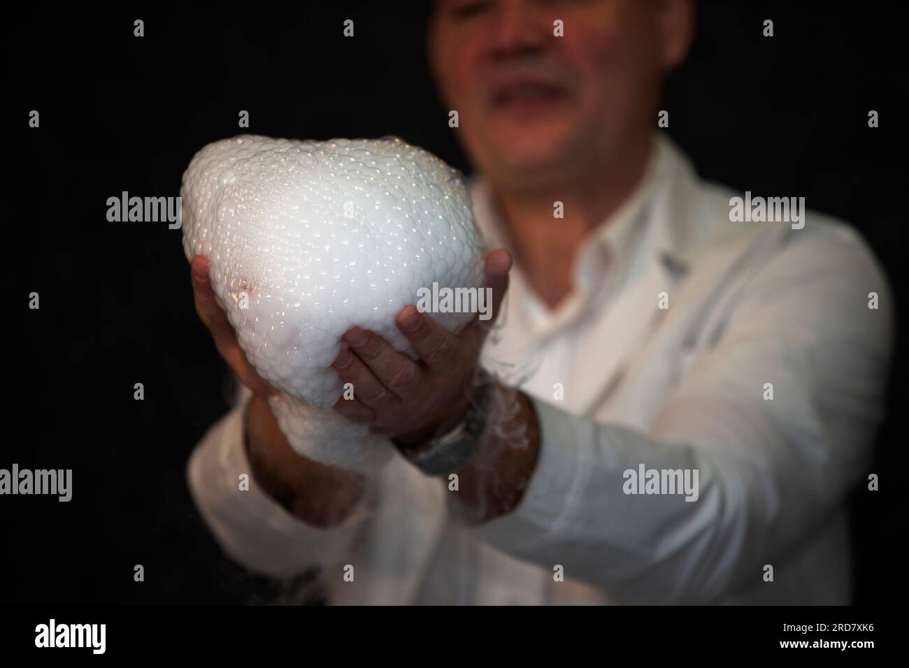 Esperimento chimico di laboratorio con schiuma e vaporizzazione.esperimento chimico di laboratorio con schiuma e vapore. Mani che trattengono la schiuma. Foto Stock