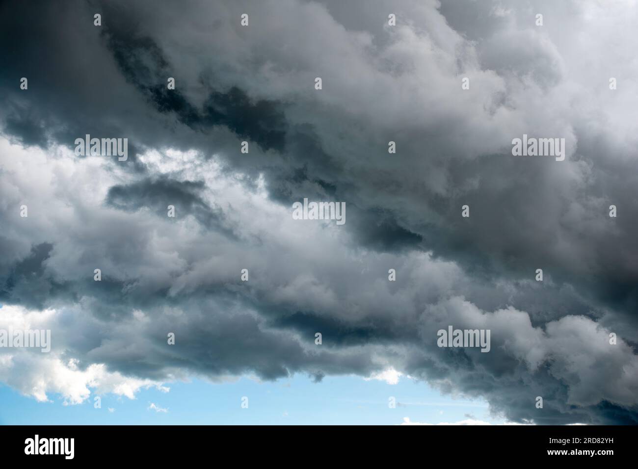 Strati minacciosi di nuvole che formano una linea retta con una striscia di cielo limpido che mostra un striscio di pioggia più scuro. Foto Stock