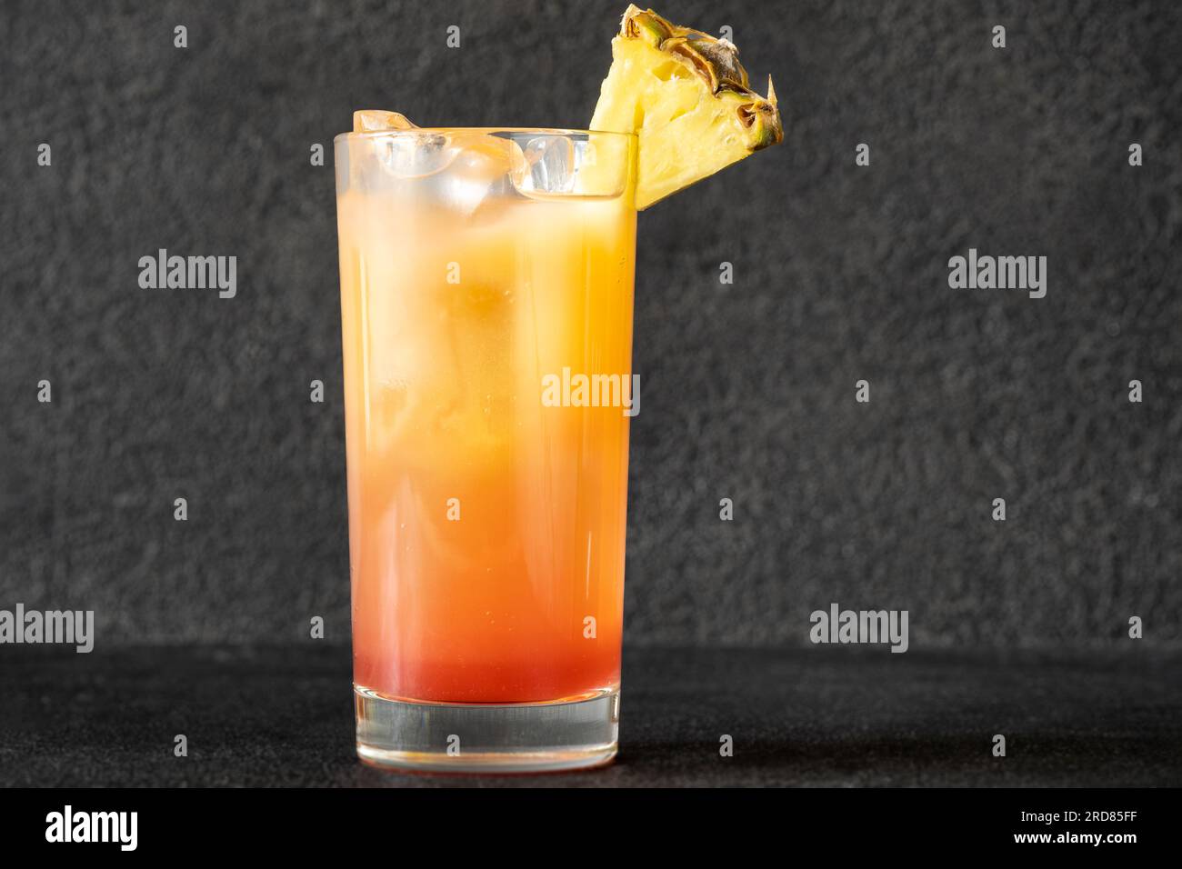 Bicchiere di Malibu Sunset cocktail guarnito con zeppa di ananas Foto stock  - Alamy