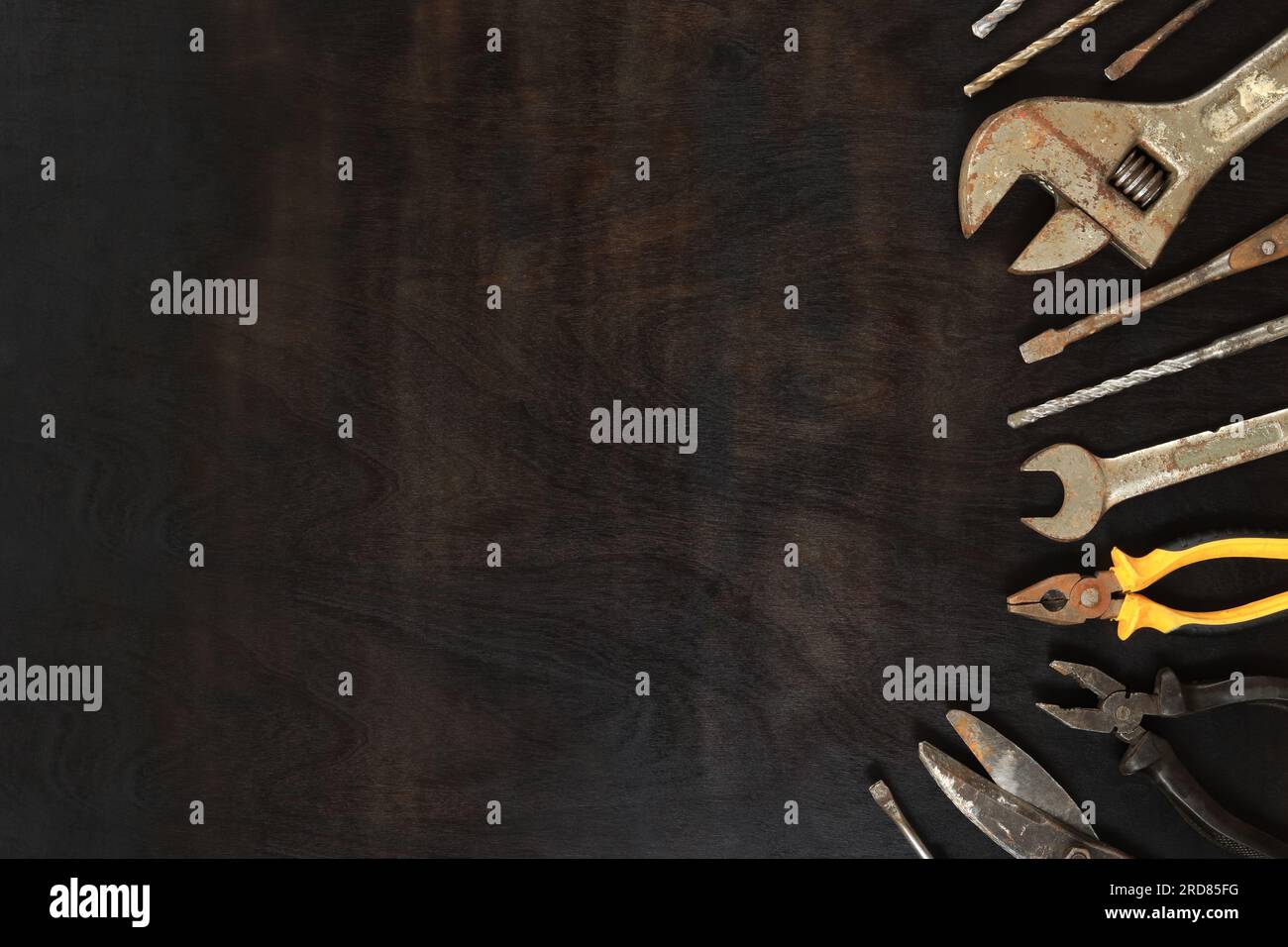 Vecchi strumenti su uno sfondo di legno scuro, vista dall'alto. Chiavi, pinze, trapano per metallo e cacciaviti. Strumenti e spazio vuoto Foto Stock