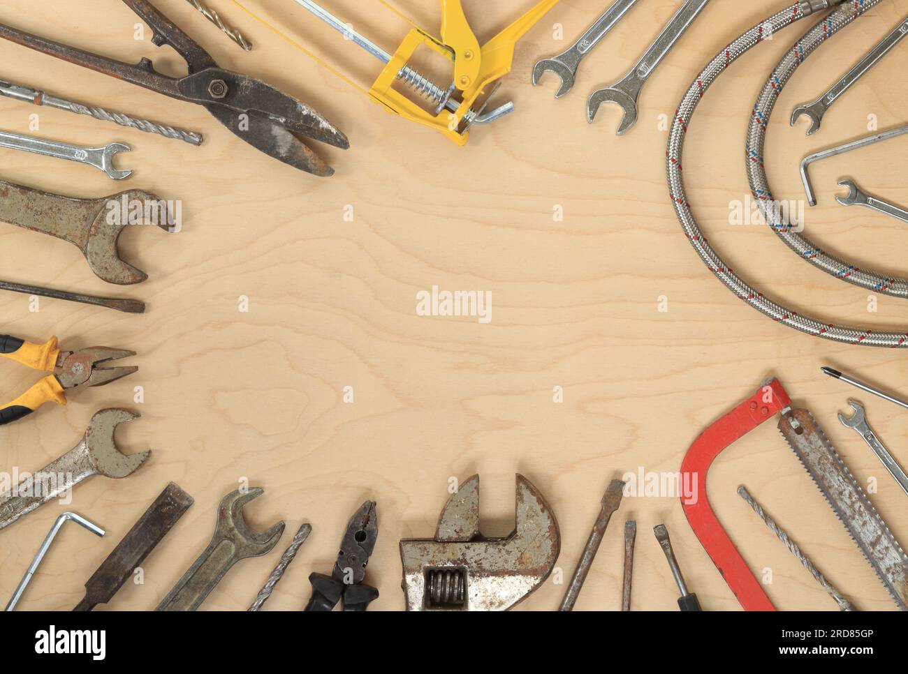 Strumenti per diversi lavori di riparazione, vista dall'alto. Vecchi attrezzi su un tavolo di legno chiaro, spazio vuoto al centro Foto Stock