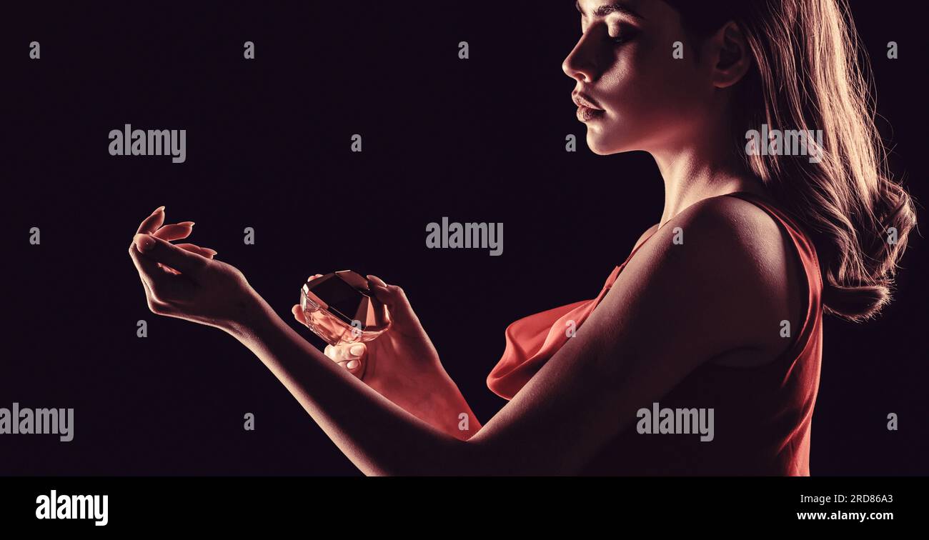 Bella ragazza che usa il profumo. Donna con una bottiglia di profumo. Flacone profumo spray donna aroma. Donna che tiene una bottiglia di profumi Foto Stock