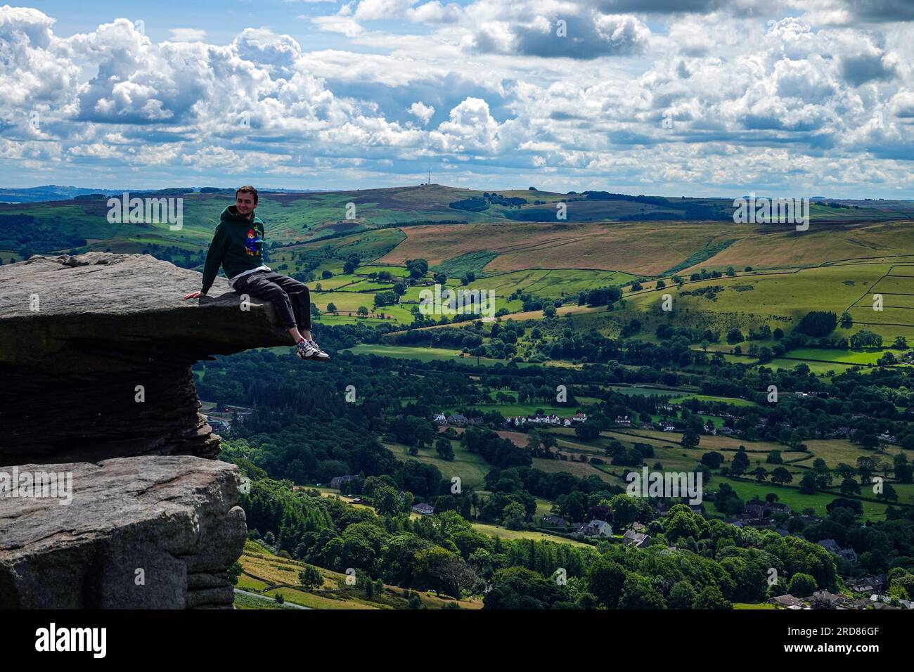 Figura maschile solitaria seduta sulla roccia nella popolare destinazione di Bamford Edge sopra il lago artificiale Ladybower, Derbyshire, The Peak District, Regno Unito Foto Stock