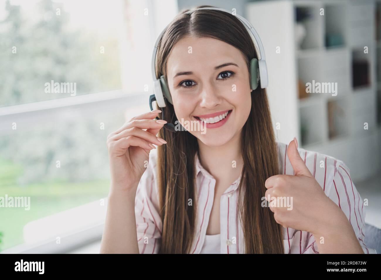 Ritratto fotografico di una giovane donna attraente che lavora con il pollice in alto vestiti eleganti eleganti e casual interni stanza accogliente ufficio domestico Foto Stock