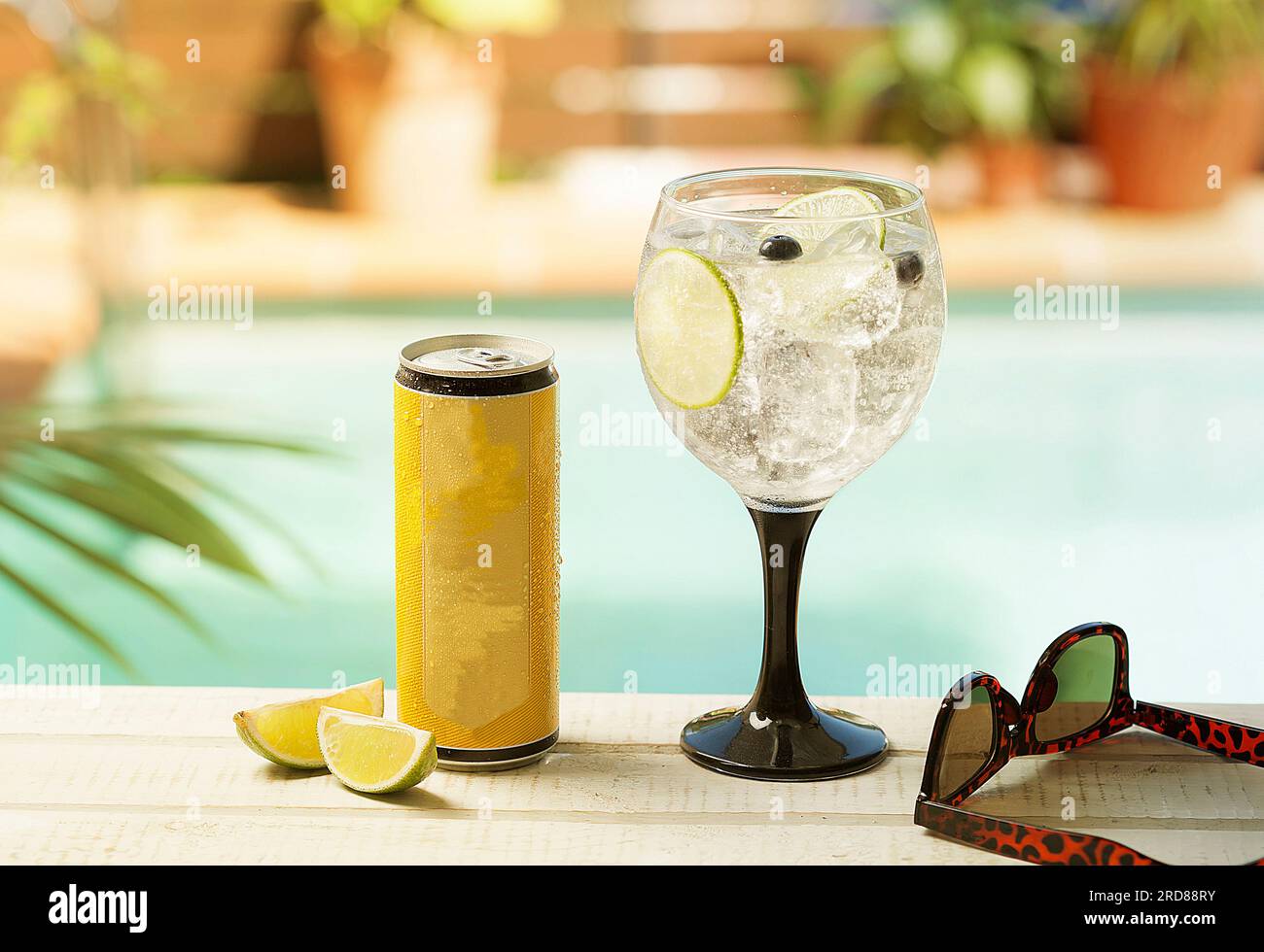 Invito a una festa in piscina: Bevande rinfrescanti in un bicchiere ai bordi della piscina Foto Stock