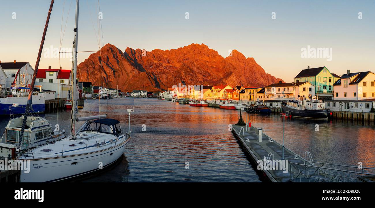 Porto e villaggio di Henningsvaer al tramonto con montagne sullo sfondo, contea del Nordland, Isole Lofoten, Norvegia, Scandinavia, Europa Foto Stock