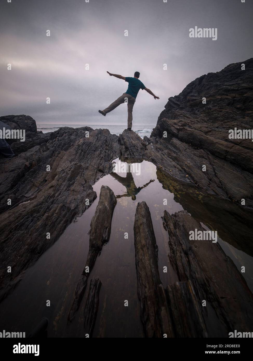Un uomo in equilibrio su una gamba sulle rocce e il suo riflesso in uno stagno d'acqua, Spagna, Europa Foto Stock