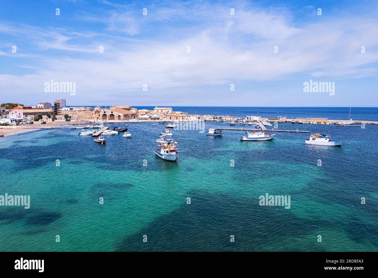 Vista aerea del porto del villaggio di pescatori di Marzamemi con barche da pesca galleggianti nelle acque turchesi, Marzamemi Foto Stock