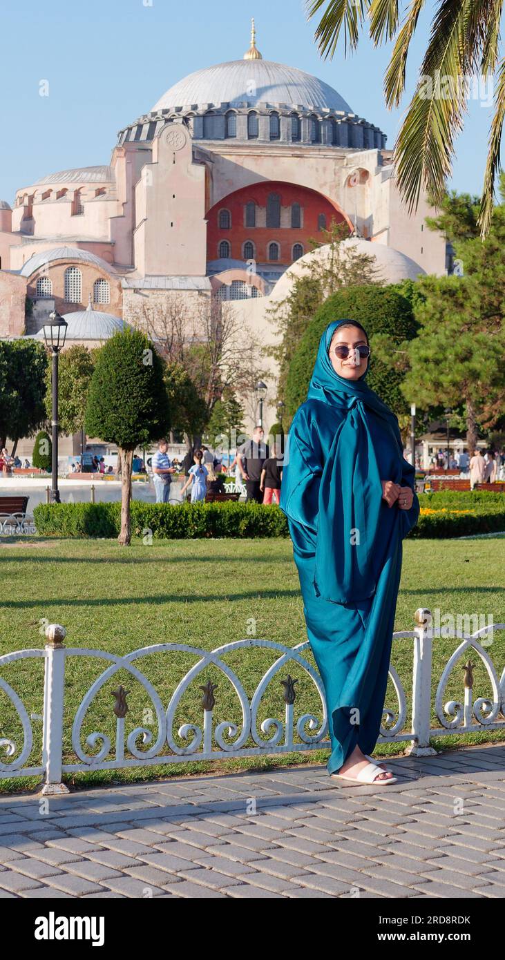Donna in abito tradizionale nel Parco Sultanahmet in una serata estiva con la moschea di Santa Sofia alle spalle, Istanbul, Turchia Foto Stock