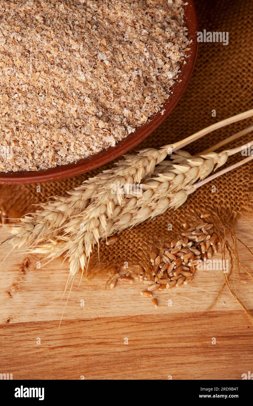 Crusca di grano in una ciotola di argilla e spighe di grano su