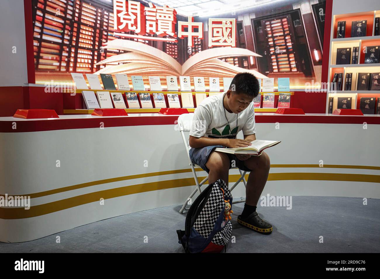 Un uomo legge un libro davanti a una cabina che vende i libri su Xi Jinping, solo presidente della Repubblica Popolare Cinese. L'Hong Kong Book Fair 2023 inizia all'Hong Kong Convention and Exhibition Centre dal 19 al 25 luglio, attirando numerose aziende ed editori che espongono i loro stand con una vasta selezione di libri. Foto Stock