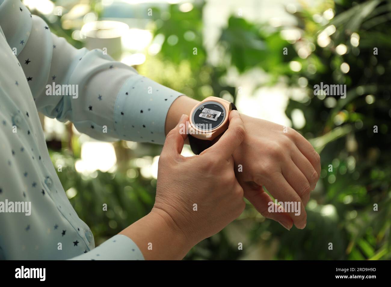 Donna che controlla il sistema di sicurezza domestica all'aperto tramite l'app smartwatch, primo piano. Immagine della stanza attraverso la telecamera CCTV sul display Foto Stock