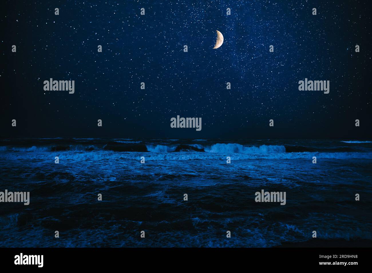 Luna a mezzaluna nel cielo stellato sul mare di notte Foto Stock