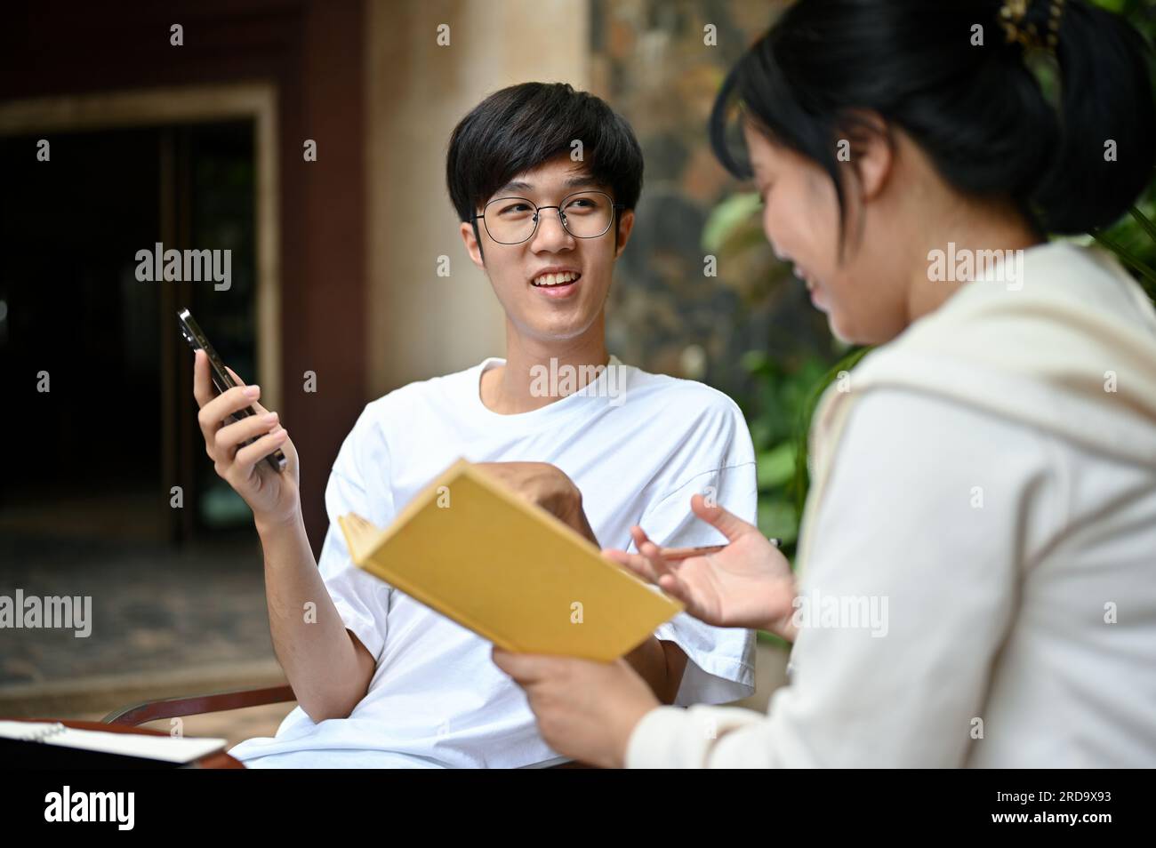 Un giovane asiatico felice ama parlare e rilassarsi a un tavolo in giardino con il suo amico nel fine settimana. Foto Stock