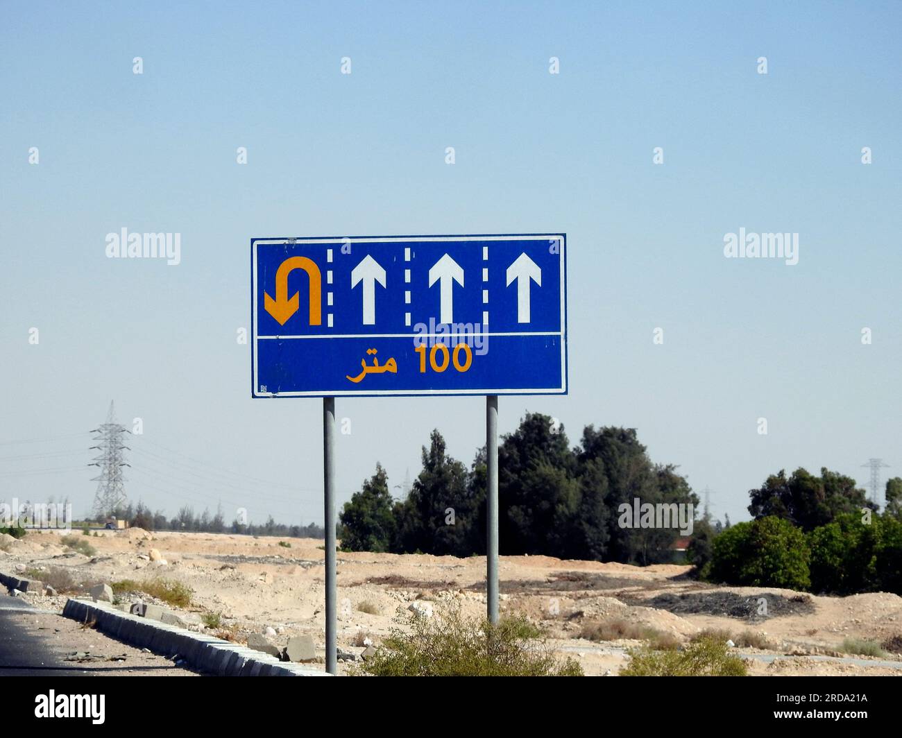 Traduzione del testo arabo (100 M cento metri) a lato di un cartello segnaletico informativo che mostra 4 corsie e indirizza i conducenti verso un u t Foto Stock