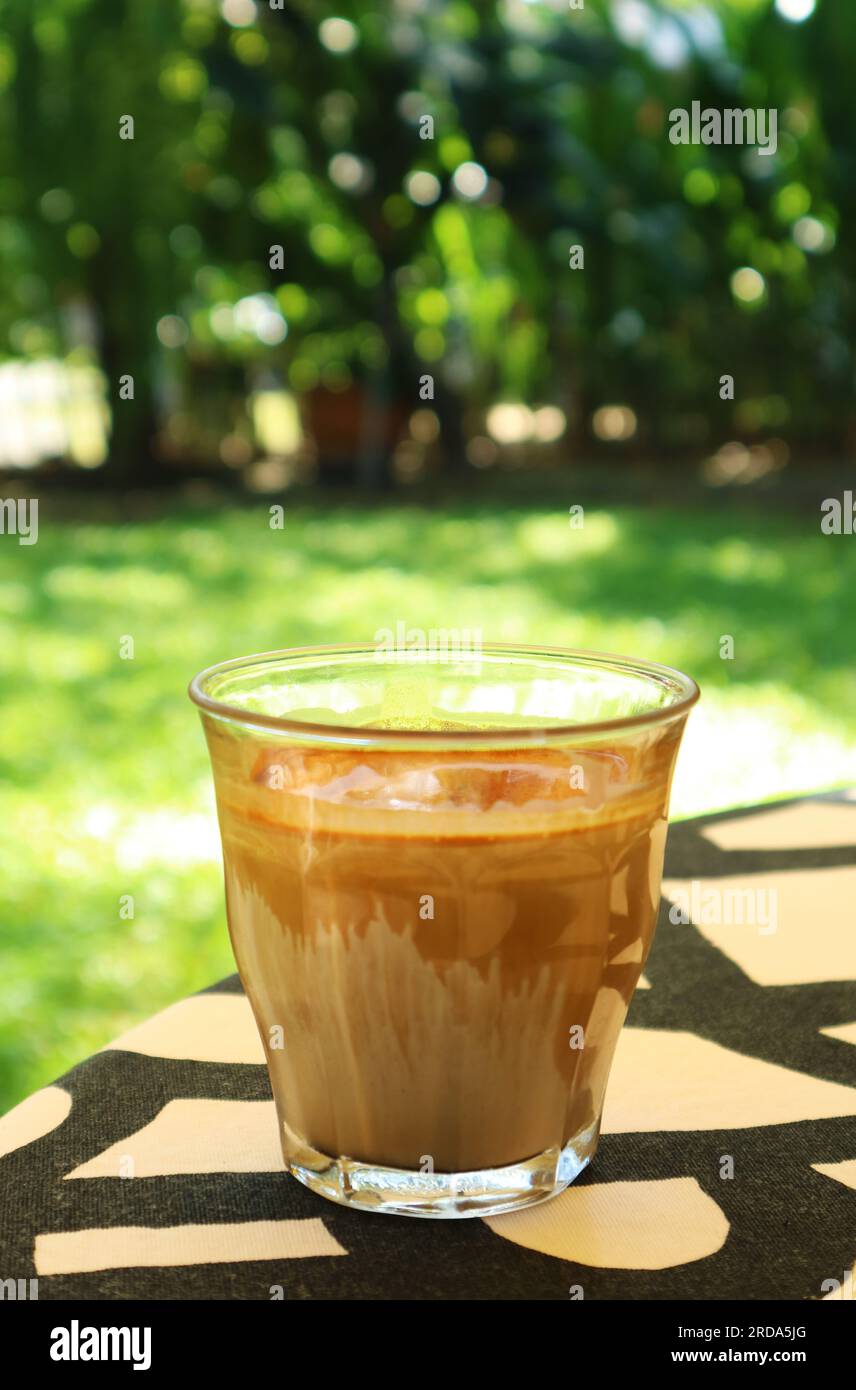 Primo piano: Un bicchiere di Dirty latte Coffee servito sul tavolo da giardino Foto Stock