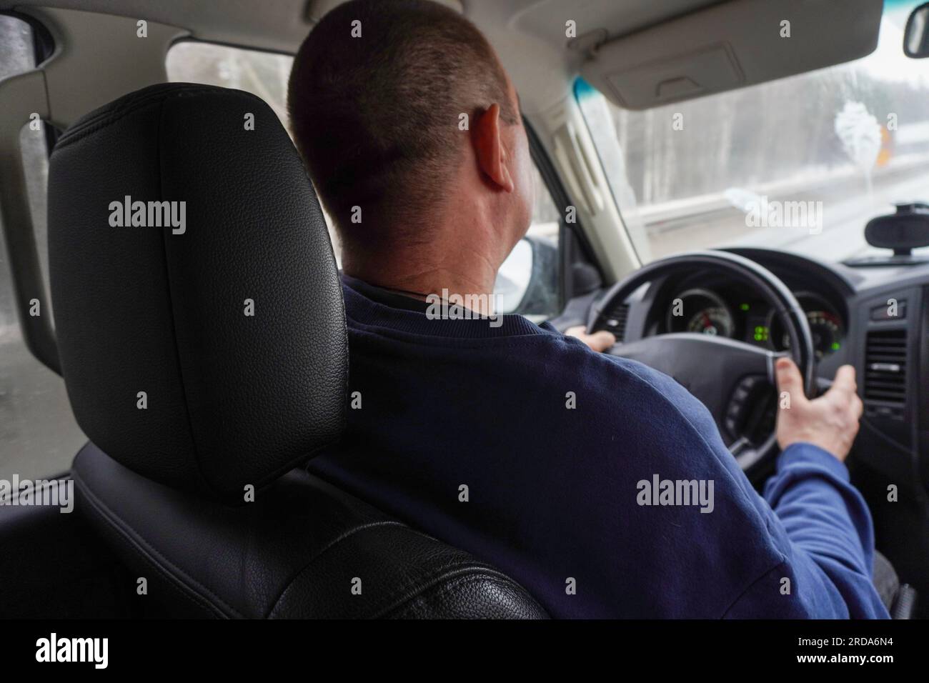 un uomo sta guidando una macchina, vista posteriore, si può vedere la pista nel finestrino Foto Stock
