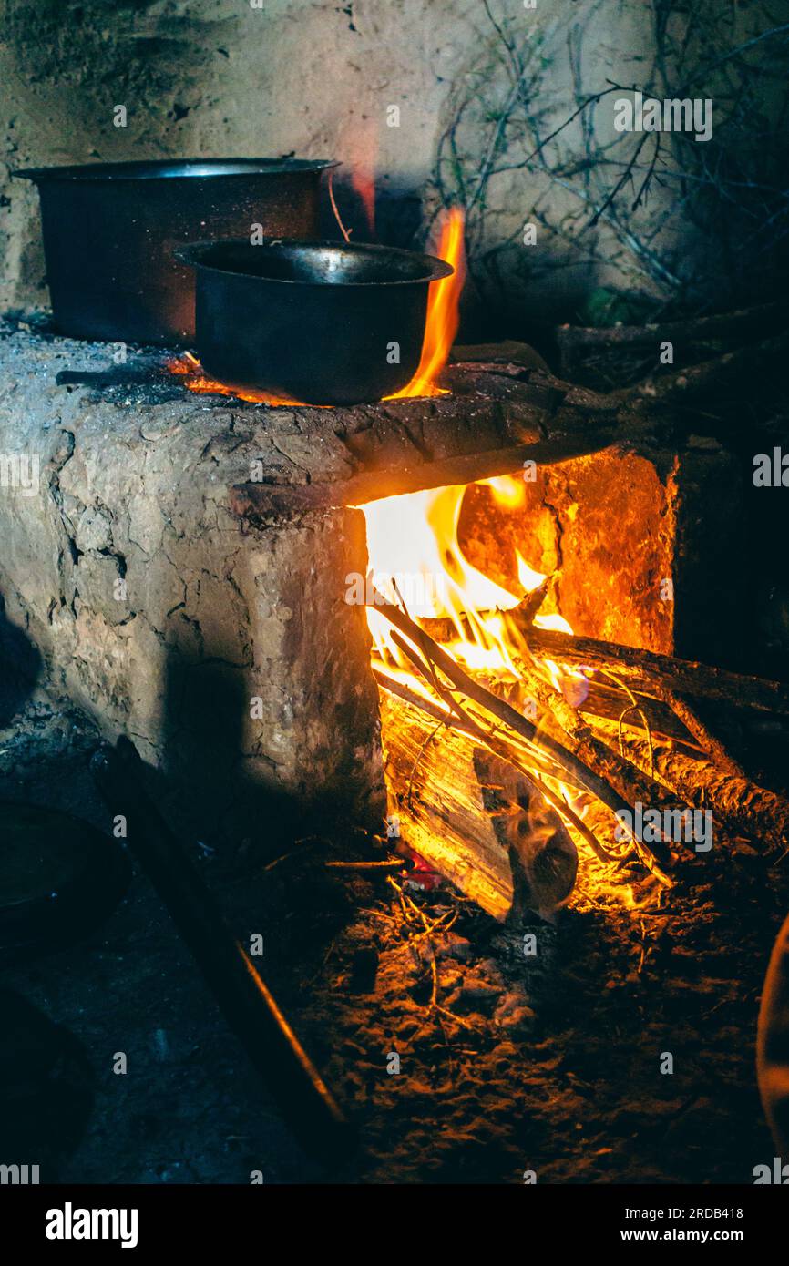 Un bellissimo camino tradizionale fatto di argilla con legno bruciato e vasi in ghisa sopra di esso. Uttarakhand India. Foto Stock