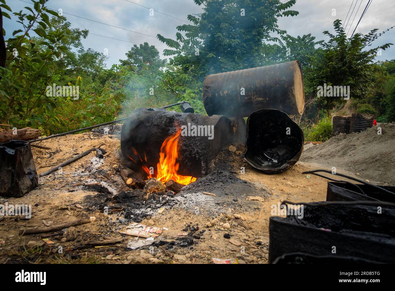 Fumo nero che esce dai barili di catrame di carbone in fiamme. Questo catrame di carbone liquefatto è comunemente usato per la costruzione di strade asfaltate in India. Foto Stock