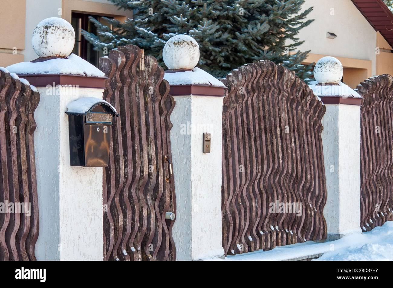 Recinzione originale fatta di tavole di legno e colonne di pietra con palle. La recinzione della casa, con una cassetta postale Foto Stock