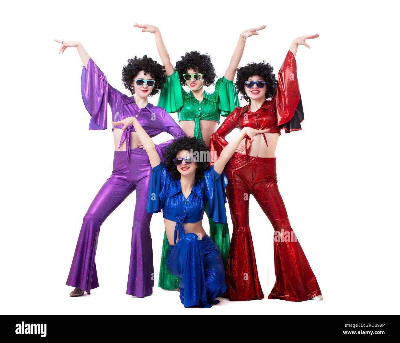 Un gruppo di ragazze con abiti svasati colorati e parrucche afro posano su uno sfondo bianco. Stile discoteca degli anni '80 o '70. Foto Stock