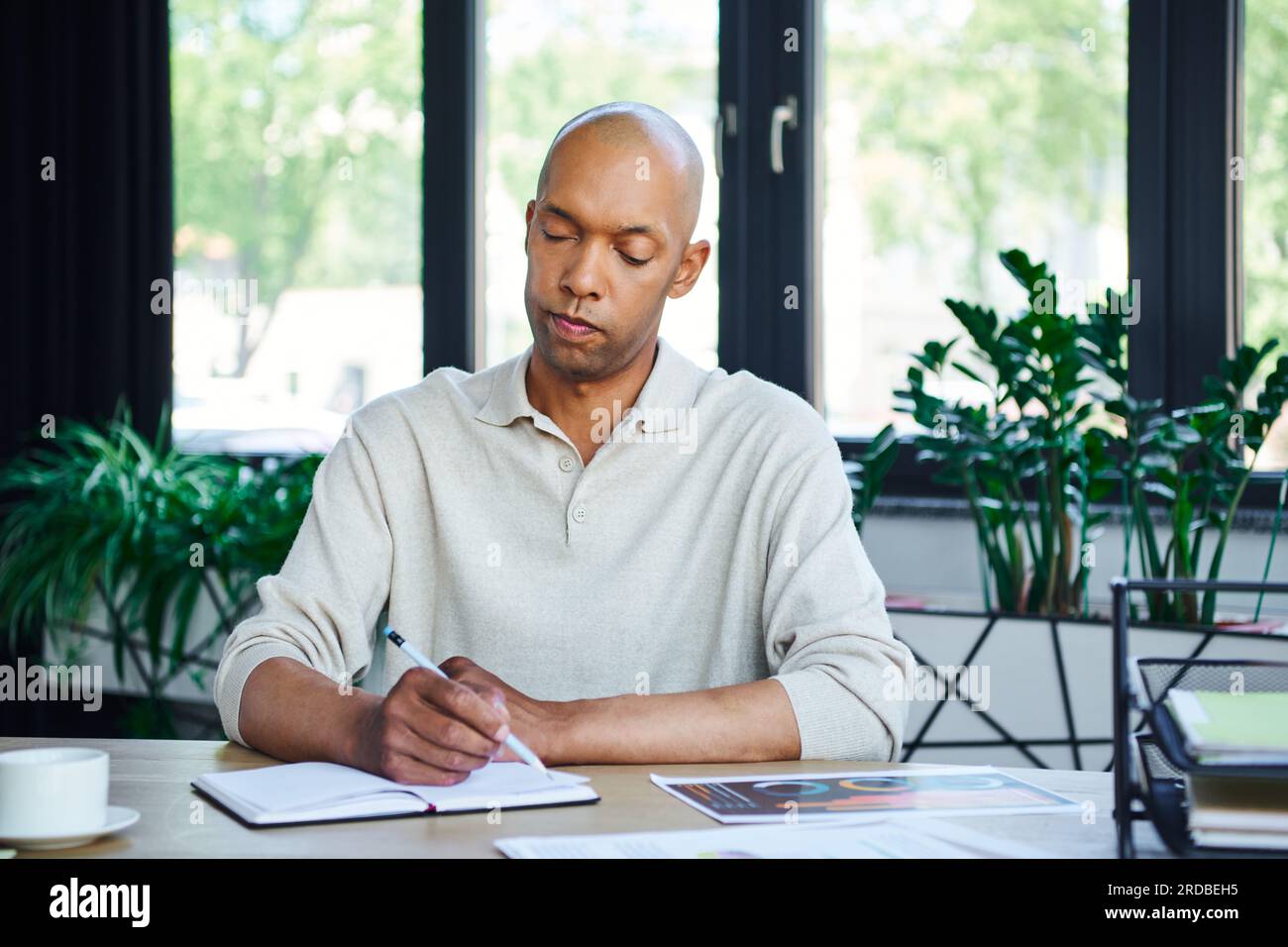 uomo con sindrome da ptosi prendendo appunti, audace uomo d'affari afro-americano al lavoro, lavoratore d'ufficio dalla pelle scura con miastenia grave malattia, diversità Foto Stock