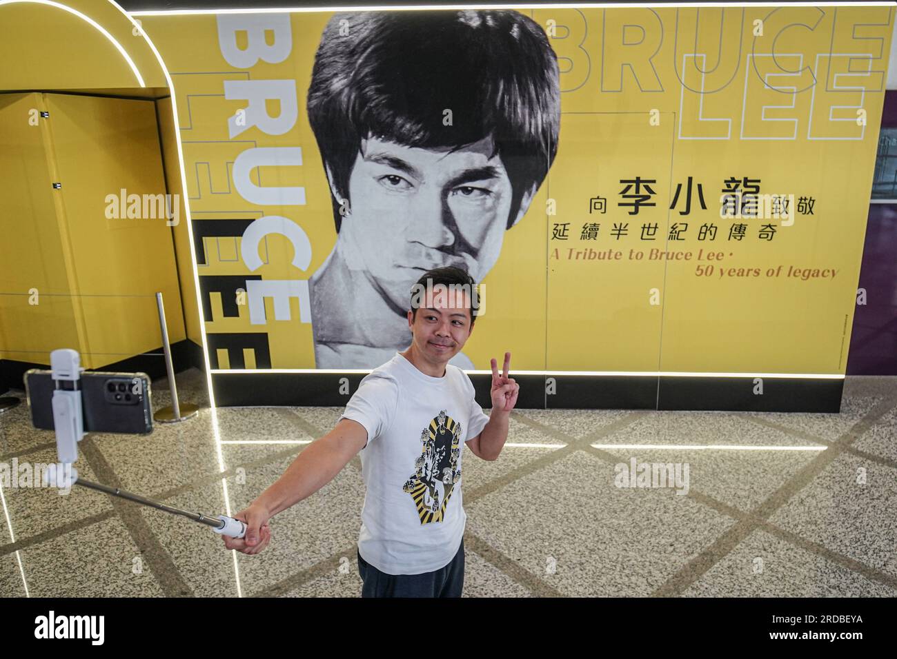 Un uomo scatta un selfie davanti a un enorme poster di Bruce Lee all
