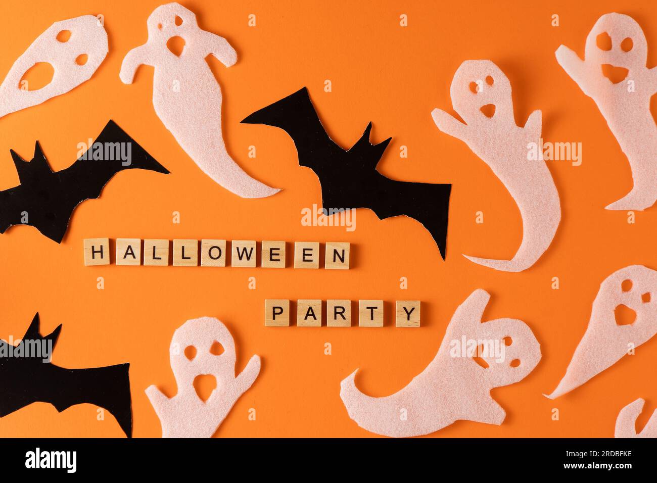 Fantasmi bianchi e mazza per la festa di Halloween. Immagine fantasma della carta di avvolgimento su sfondo arancione vista dall'alto. Fumetto Creepy Whisper. Fai-da-te fatto a mano. Impostare i caratteri boo. Parola frase di legno della lettera. Foto Stock