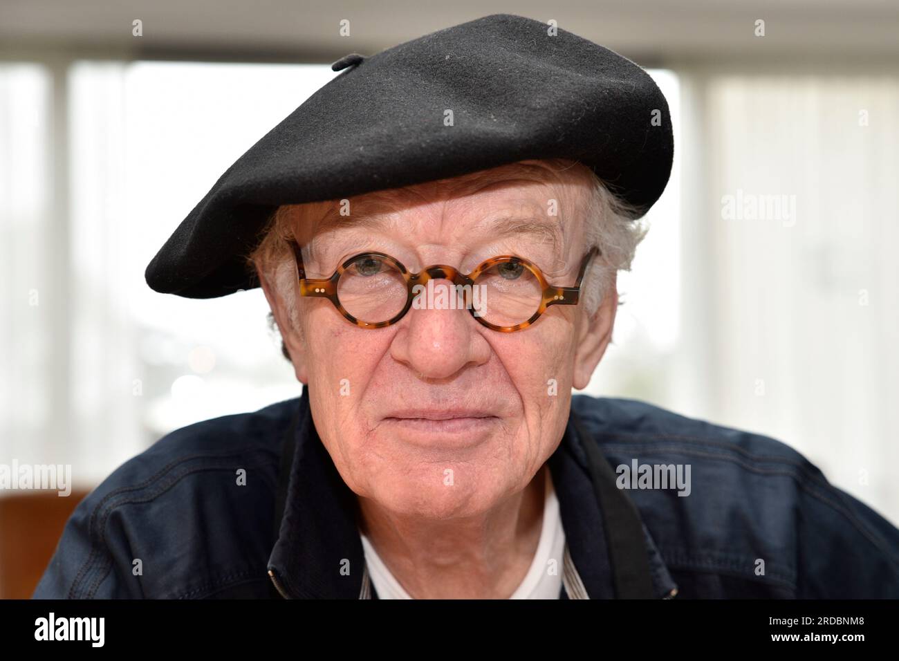 Ritratto di un uomo più anziano con capelli ricci grigi, un cappello alpino basco francese e occhiali rotondi fiamme Foto Stock