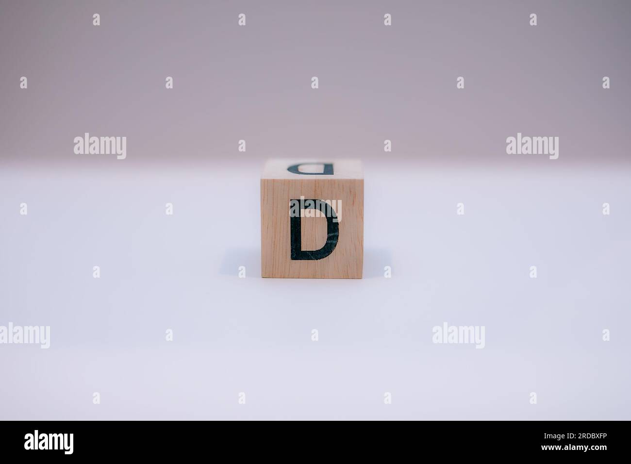 Blocco di legno scritto "D" con sfondo bianco. Foto Stock