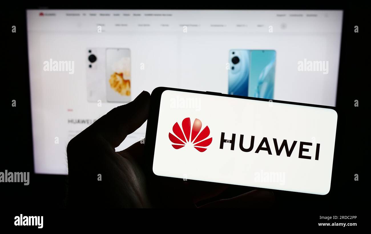 Persona che possiede uno smartphone con il logo della società cinese Huawei Technologies Co. Ltd. Sullo schermo davanti al sito Web. Concentrarsi sul display del telefono. Foto Stock