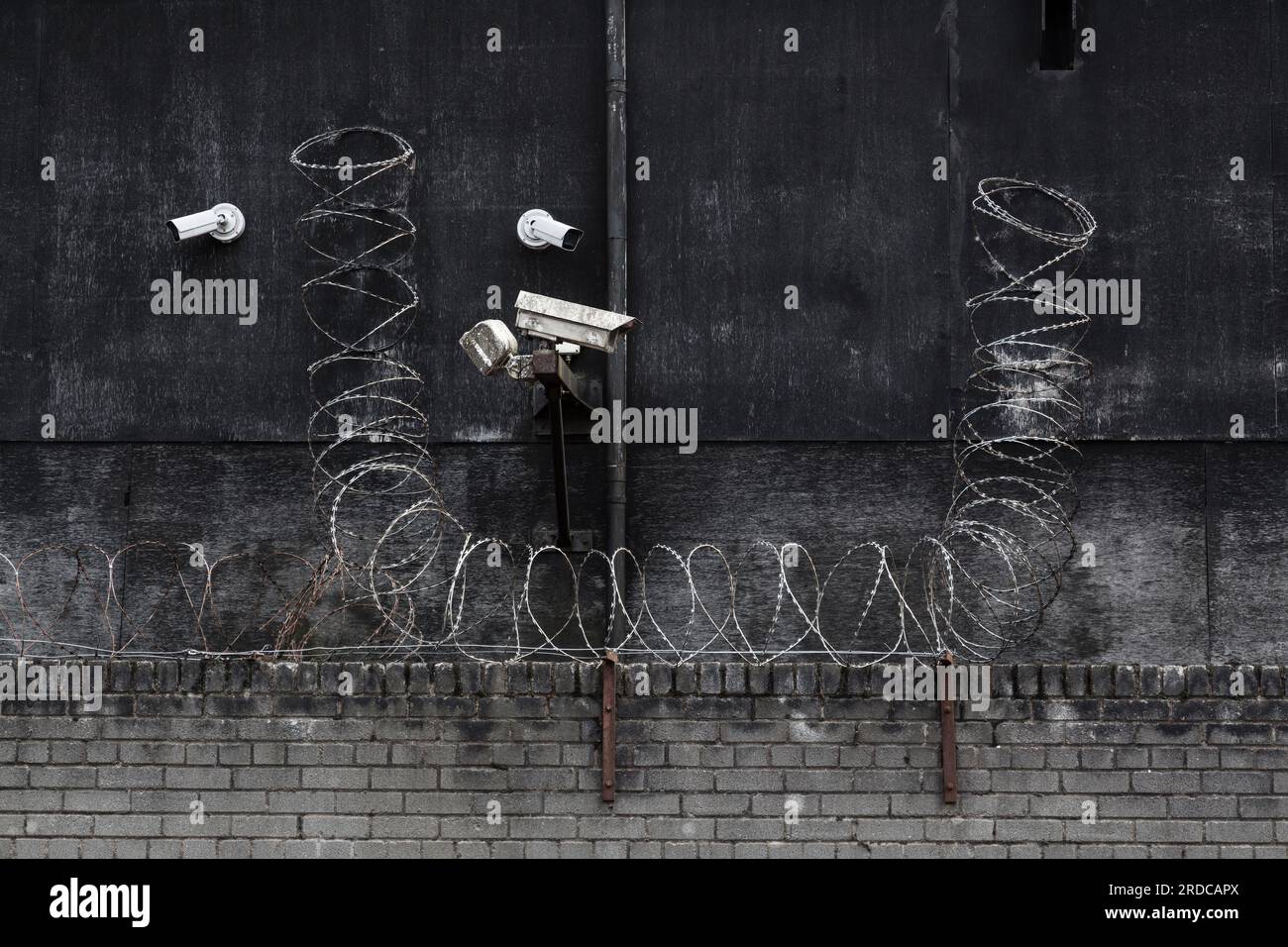 Telecamere di sicurezza CCTV e filo spinato all'esterno di un edificio di fabbrica, Regno Unito Foto Stock
