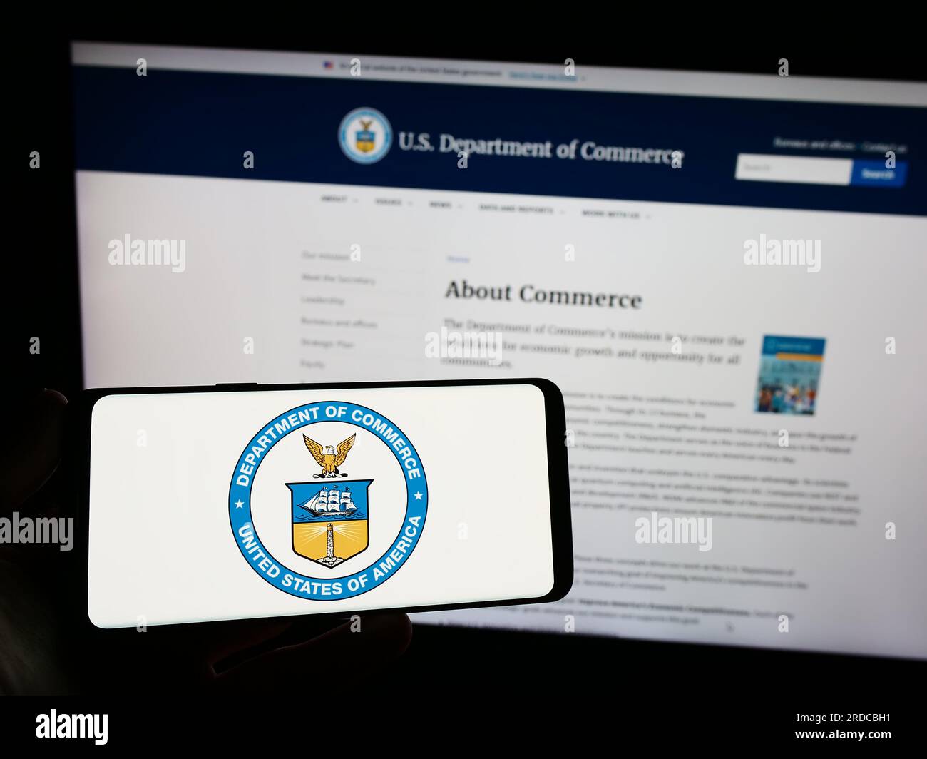 Persona che tiene lo smartphone con il sigillo del Dipartimento del commercio degli Stati Uniti (DOC) sullo schermo di fronte al sito Web. Concentrarsi sul display del telefono. Foto Stock Persona che tiene lo smartphone con il sigillo del Dipartimento del commercio degli Stati Uniti (DOC) sullo schermo di fronte al sito Web. Concentrarsi sul display del telefono. Foto Stock