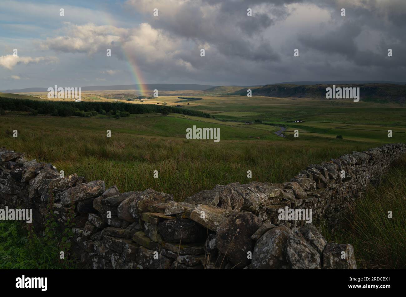 Rainbow sopra i North Pennines. Campi illuminati da luce transitoria. Foto Stock