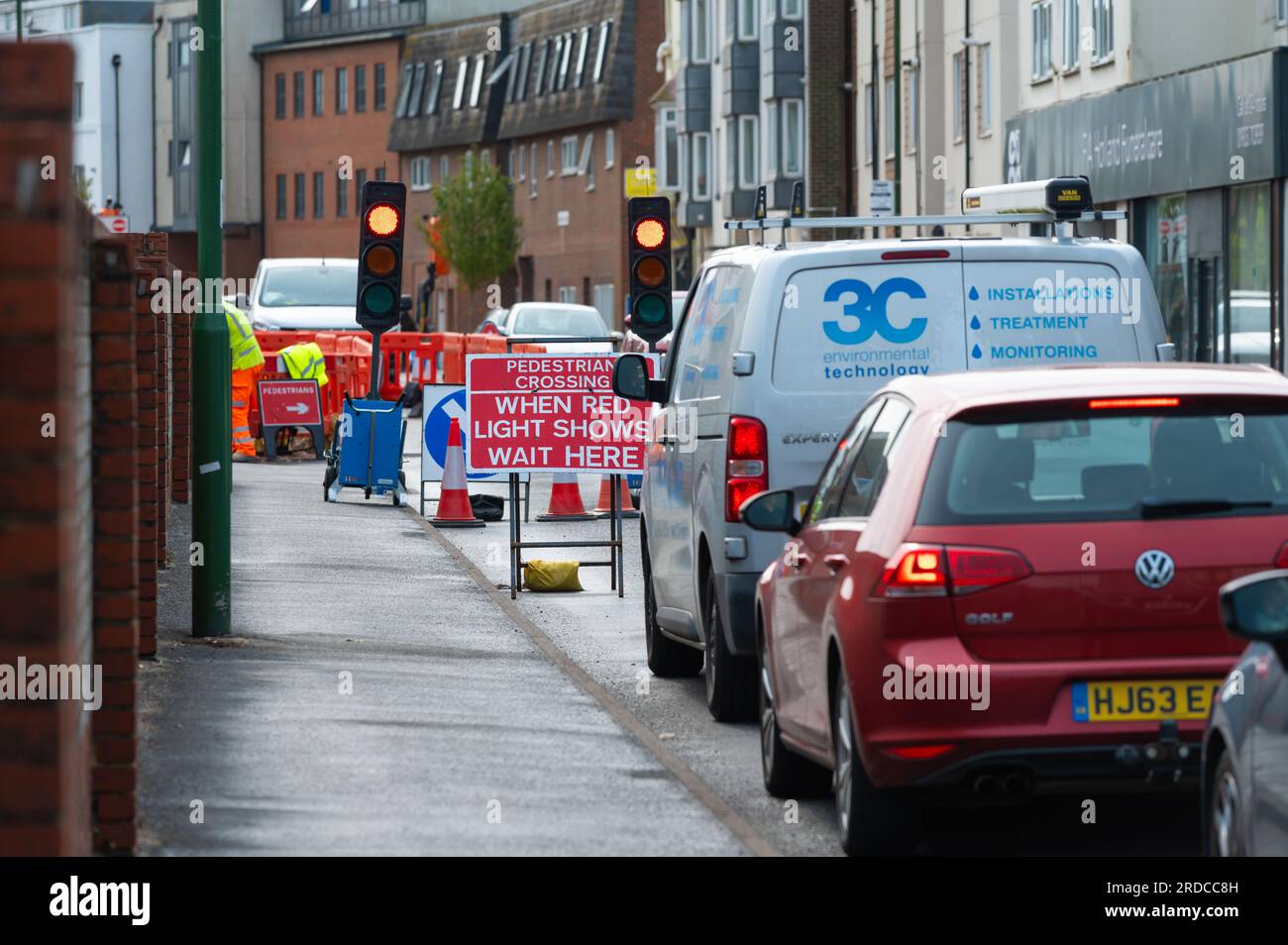 Auto e veicoli in coda o in attesa ai semafori rossi temporanei su una strada britannica durante i lavori stradali in una trafficata città, nel Regno Unito. Foto Stock