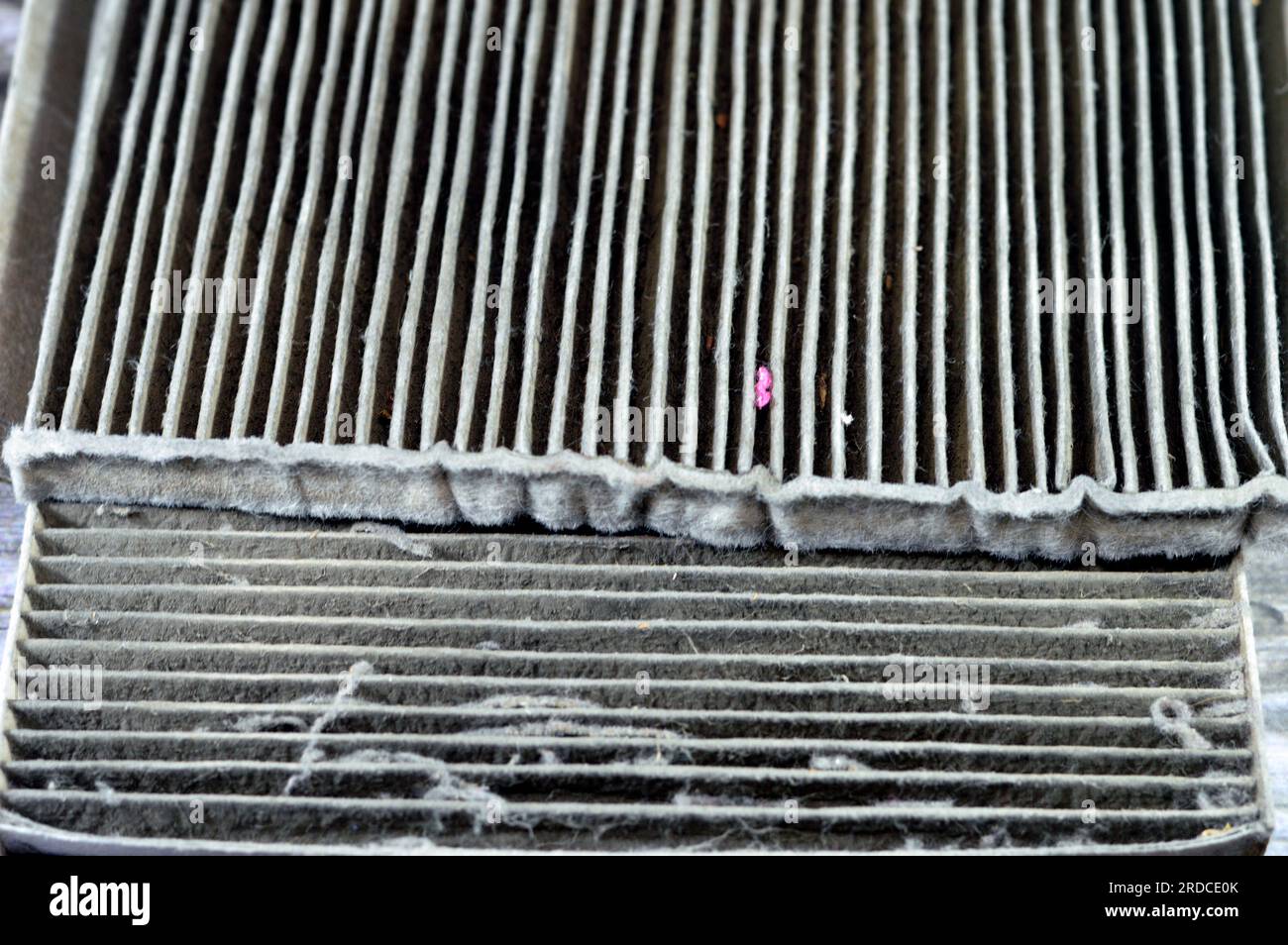 Vecchio filtro dell'aria condizionata dell'auto usata pieno di polvere rimosso dal veicolo per essere sostituito con un nuovo filtro a carboni attivi dell'abitacolo, retingula Foto Stock