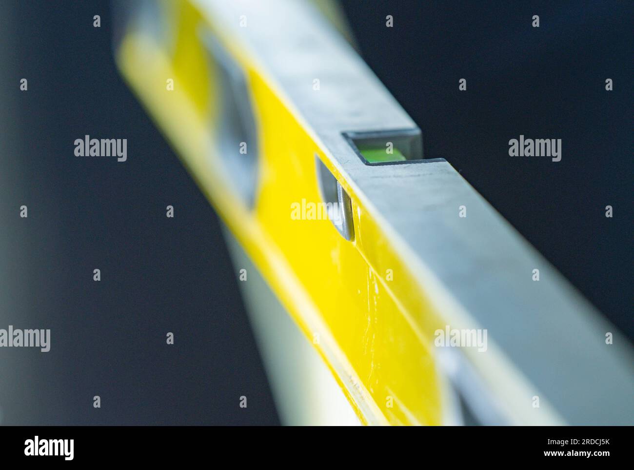 Livello di costruzione isolato su sfondo scuro tenuto in sfondi industriali manuali sfondi di progettazione grafica Foto Stock