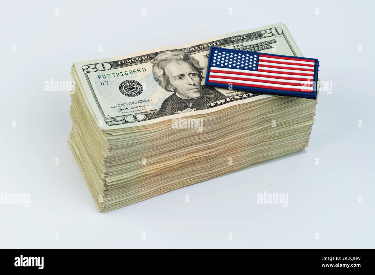 Bandiera americana su una pila di banconote da 20 dollari isolata su sfondo bianco Foto Stock