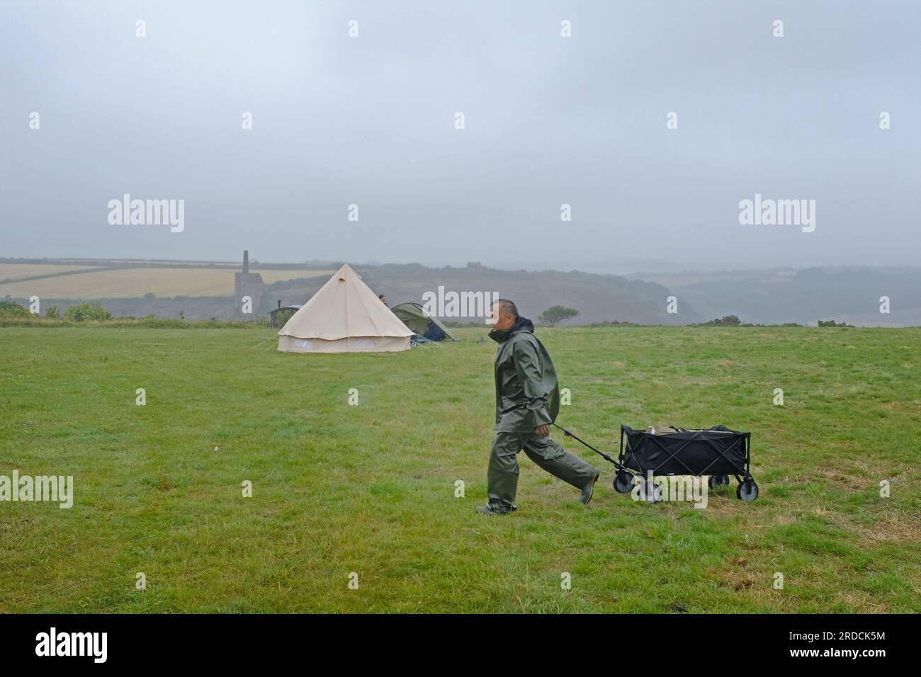 Un frequentatore di festival che lascia un campo vuoto con il maltempo. Foto Stock
