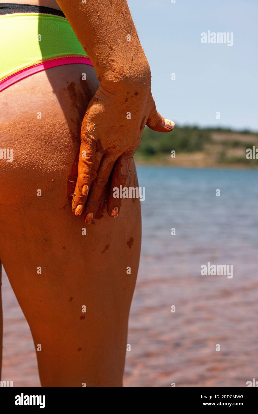 Bagno di fango riabilitante, esfoliante e curativo sulla pelle di una donna, in un lago a Castilla y León in Spagna. di argilla Foto Stock