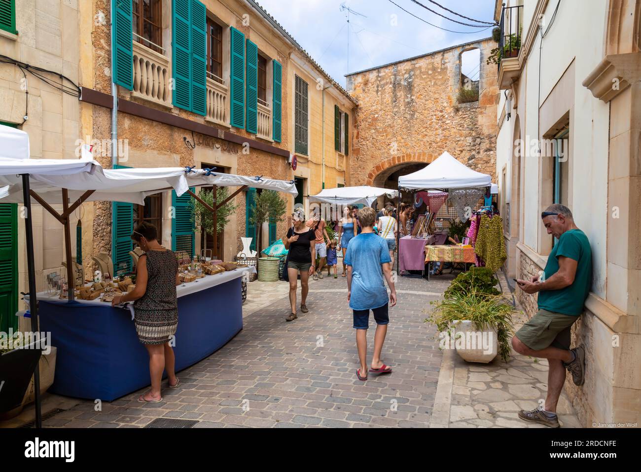 Le persone passeggiano lungo una stradina intima fiancheggiata da bancarelle di merci nella pittoresca cittadina di Santanyí, sull'isola mediterranea di Maiorca, a SP Foto Stock