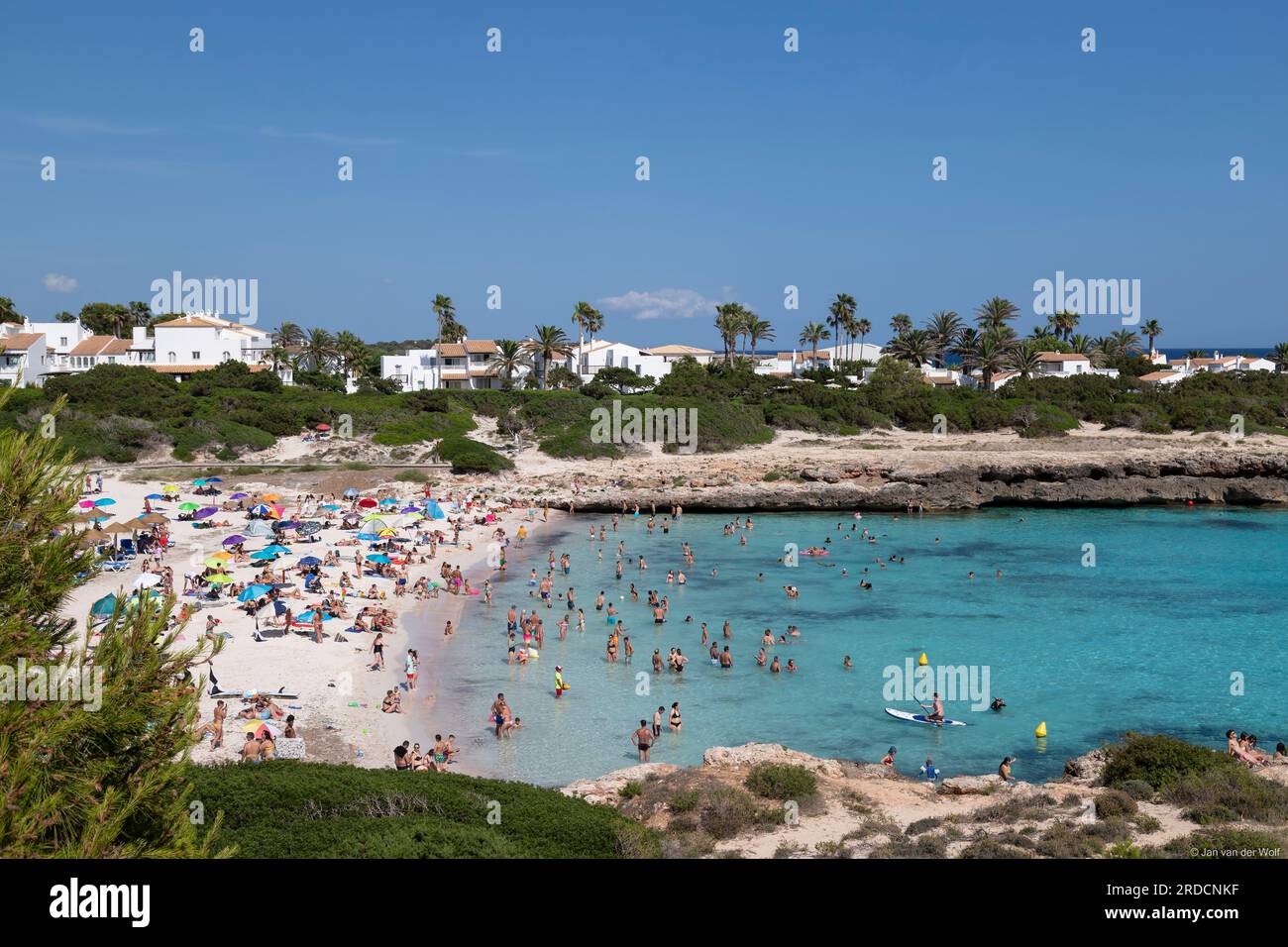 I turisti si godono l'acqua di mare nella località di Cala en Bosc sull'isola spagnola di Minorca. Foto Stock
