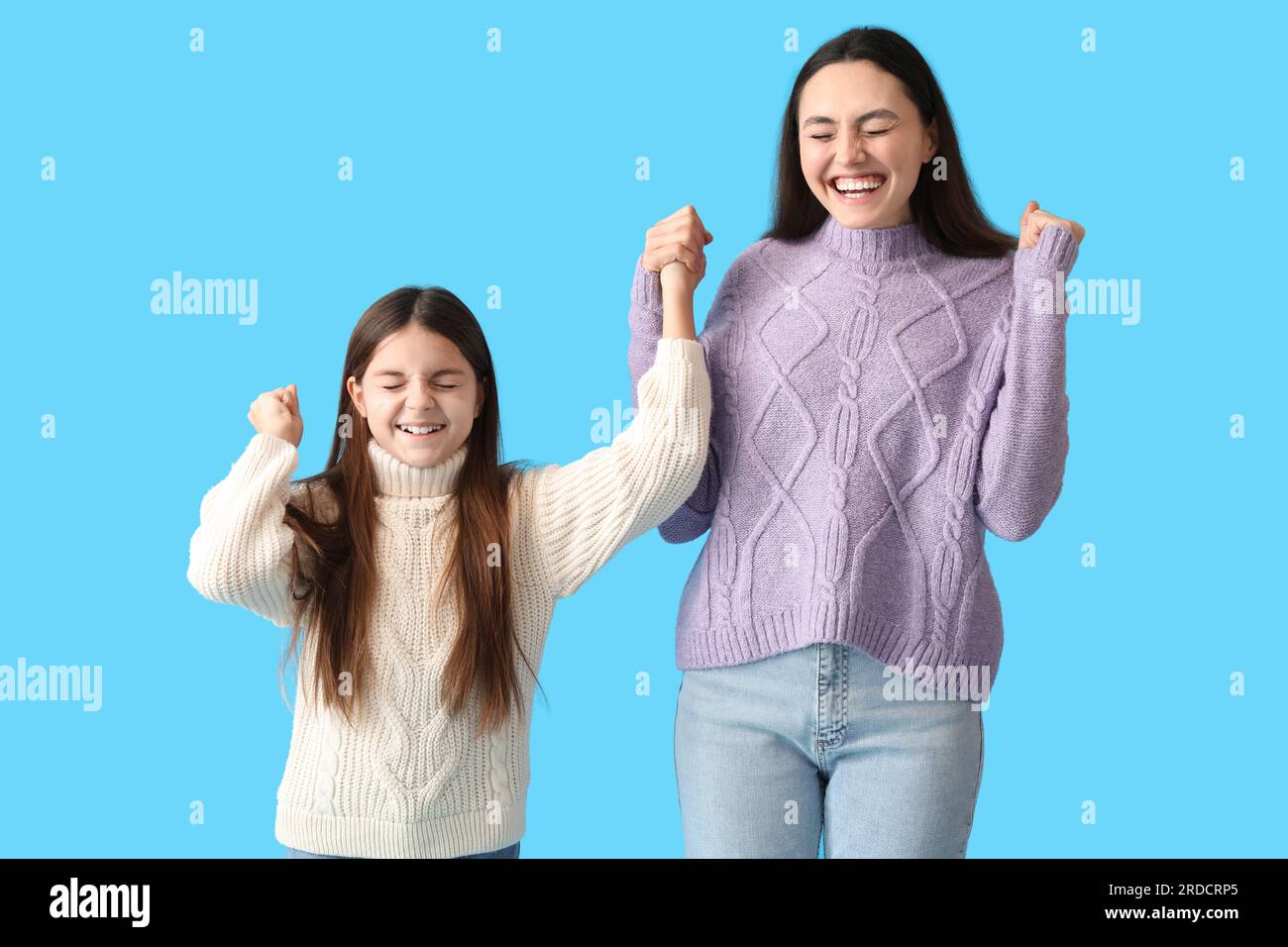 Bambina felice e sua madre con maglioni caldi su sfondo blu Foto stock -  Alamy