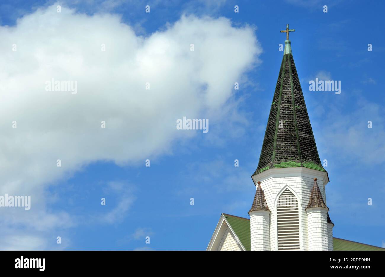 L'immagine di sfondo mostra il campanile della Chiesa di Cristo ad Hancock, Michigan. Il campanile è di forma conica con finitura a croce. Il cielo blu circonda il pioppo Foto Stock