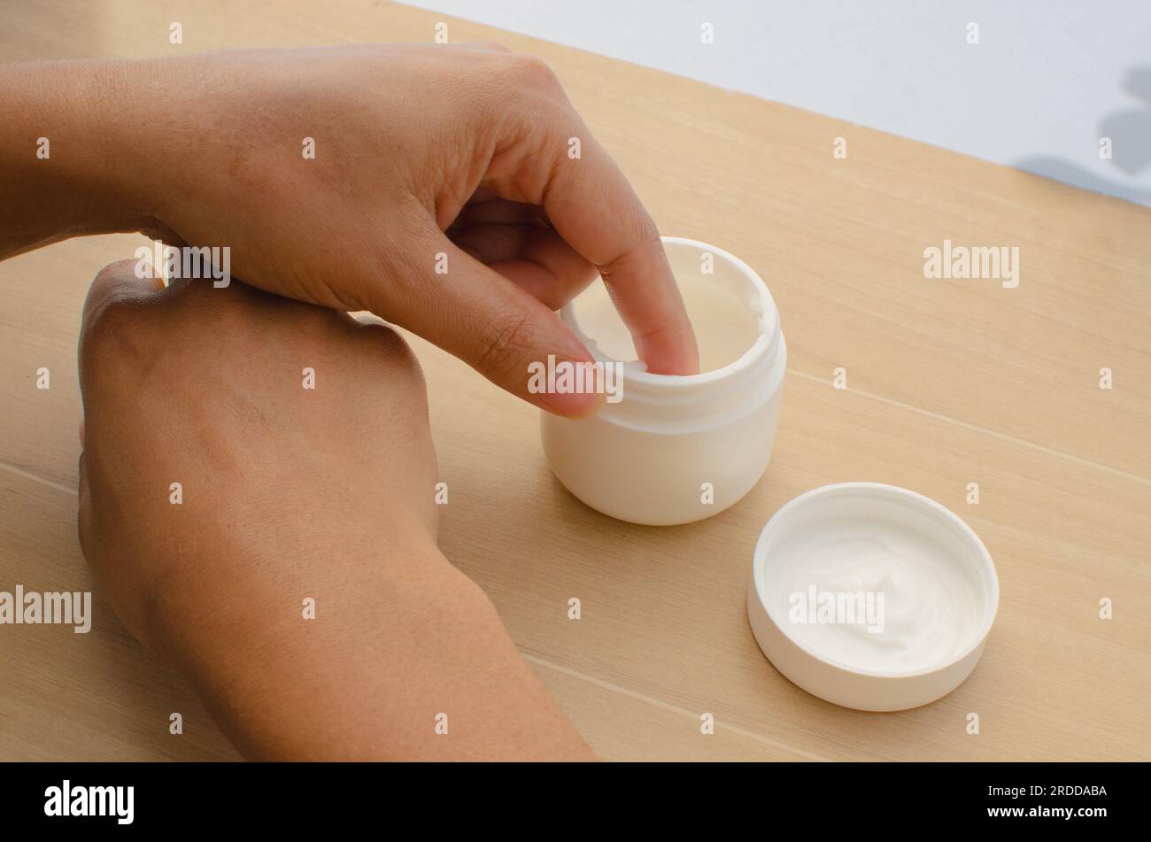 Primo piano di mani che distribuiscono una crema idratante per promuovere una pelle sana e nutrita. Foto Stock