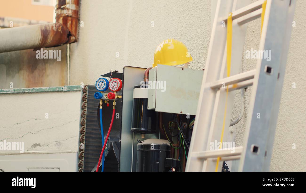 Malfunzionamento del condensatore con coperchio di protezione rimosso in caso di necessità di manutenzione con parti interne elettriche bruciate. Aria condizionata esterna in attesa di essere ristrutturata accanto alle attrezzature tecniche Foto Stock